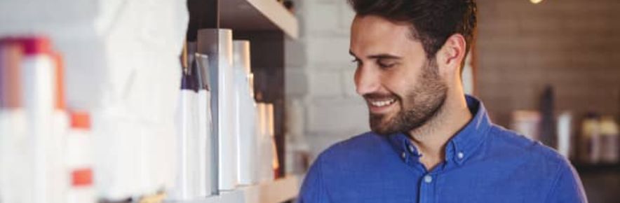 professionnel de la coiffure regardant ses produits sur une étagère en souriant
